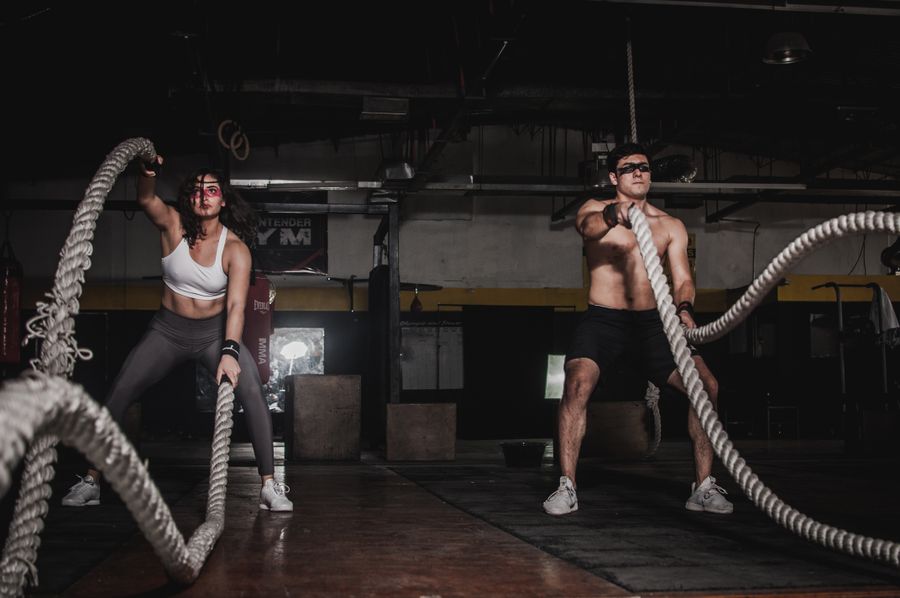 Two members working battle ropes during a coached session