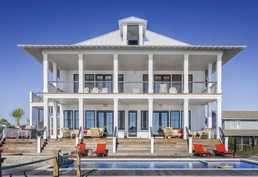 White two-storey villa with veranda and poolside loungers